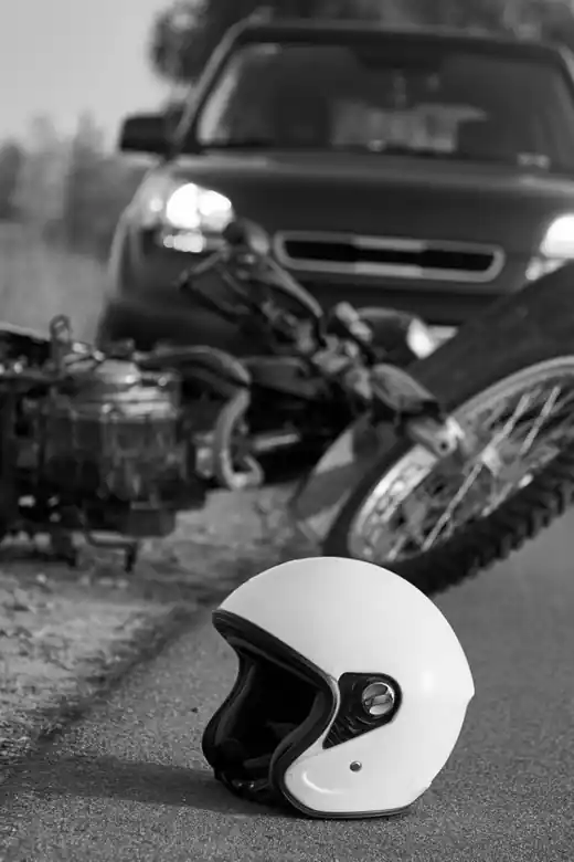 Casco en el asfalto junto a una moto caída y un auto detenido